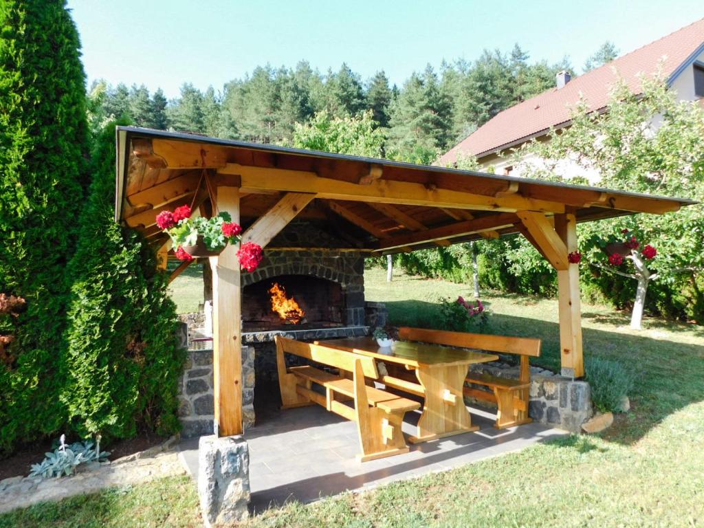 Drvena sjenica sa zidanim roštiljem, stolom i klupama u vrtu